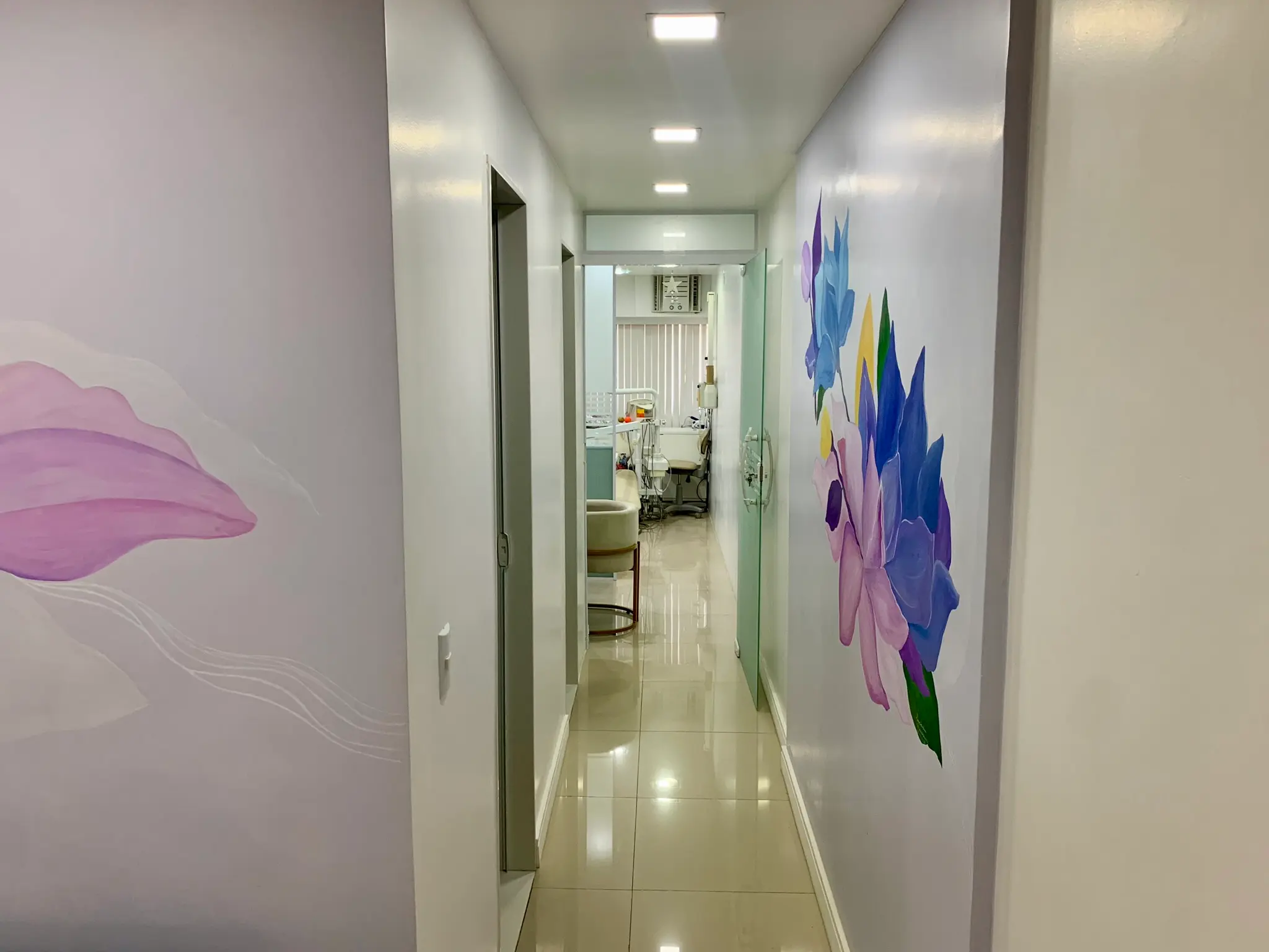 Corredor do consultório com murais de flores pintados nas paredes